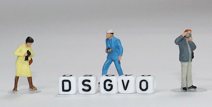 Titelbild stellt 3 Figuren dar, die um Buchstabenwürfel herumstehen, die das Wort DSGVO bilden